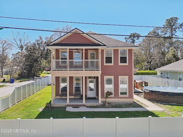 view of front of property featuring a fenced front yard, a fenced in pool, a front yard, a patio area, and a balcony