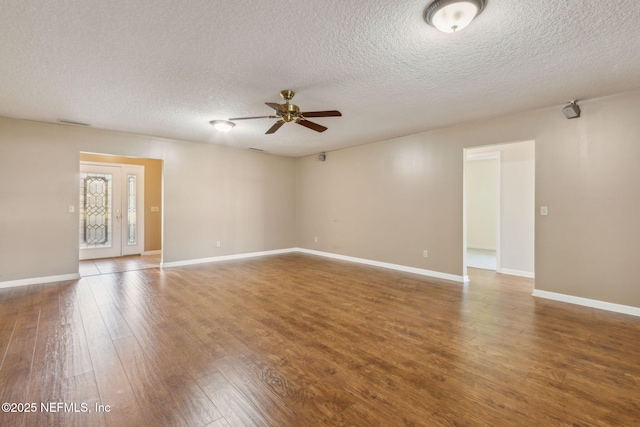 empty room with dark wood-style floors, visible vents, baseboards, and a ceiling fan