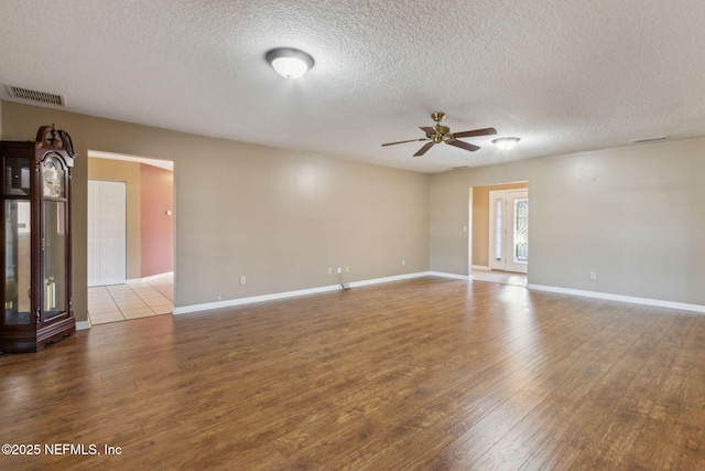 unfurnished room with light wood-type flooring, baseboards, visible vents, and a ceiling fan