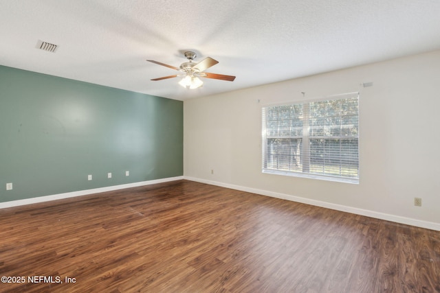 empty room with dark wood-style floors, ceiling fan, a textured ceiling, and baseboards