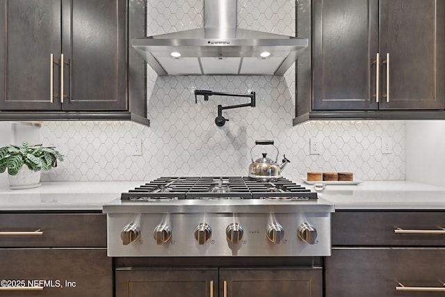 kitchen with dark brown cabinets, wall chimney range hood, light countertops, and stainless steel gas stovetop