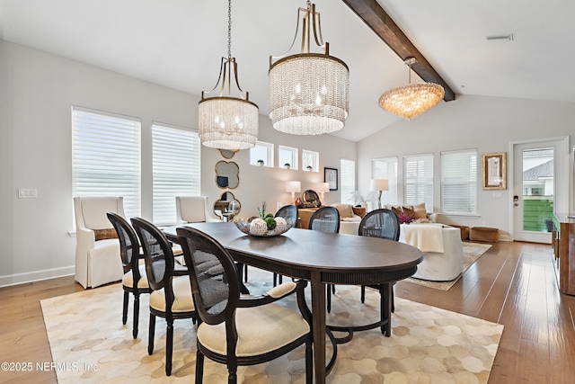 dining room with lofted ceiling with beams, a notable chandelier, light wood-style flooring, and baseboards