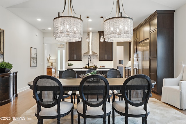 dining space with light wood-style flooring, a chandelier, baseboards, and recessed lighting