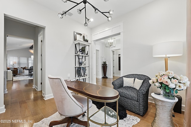 sitting room with lofted ceiling, an inviting chandelier, baseboards, and wood finished floors