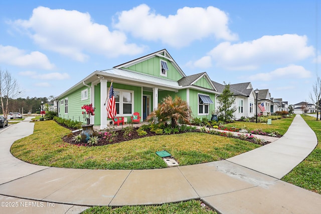 view of front of home featuring metal roof, a porch, a residential view, board and batten siding, and a front yard