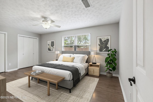 bedroom with visible vents, baseboards, two closets, and wood finished floors