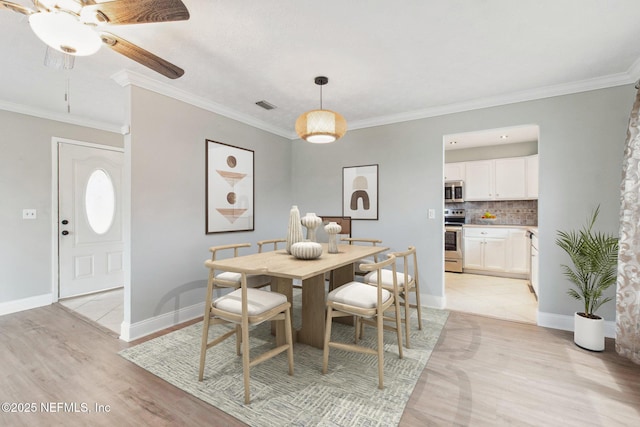 dining room featuring crown molding, light wood-type flooring, visible vents, and ceiling fan