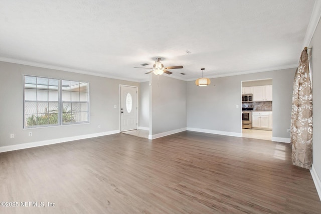 unfurnished living room featuring baseboards, wood finished floors, a ceiling fan, and ornamental molding