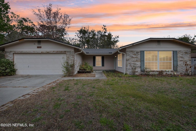 single story home featuring an attached garage, a lawn, brick siding, and driveway