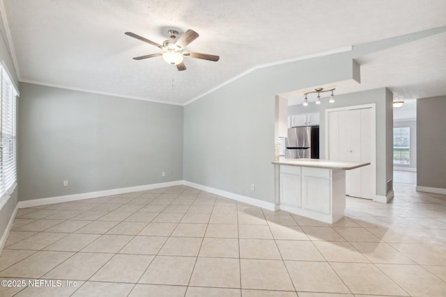 unfurnished living room with light tile patterned floors, a ceiling fan, baseboards, vaulted ceiling, and a textured ceiling