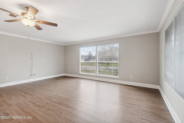 spare room with visible vents, crown molding, baseboards, and wood finished floors