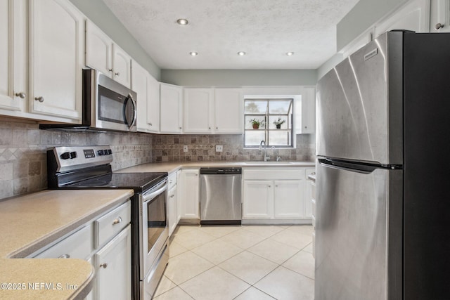 kitchen with light tile patterned floors, backsplash, stainless steel appliances, and a sink