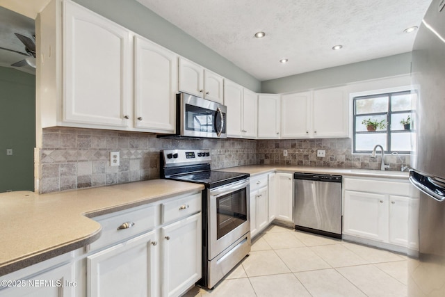 kitchen with decorative backsplash, white cabinets, appliances with stainless steel finishes, and a sink