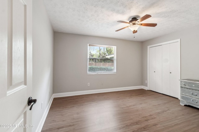 unfurnished bedroom featuring wood finished floors, baseboards, and a textured ceiling