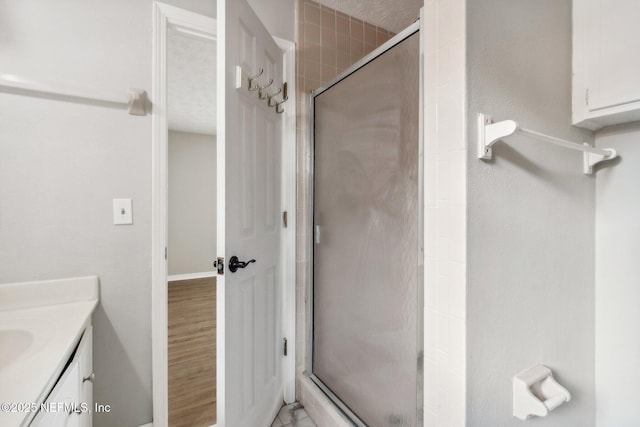 full bath with a shower stall, vanity, and wood finished floors