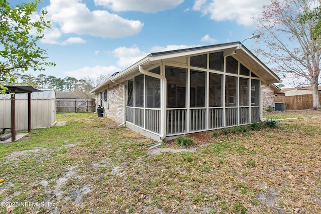 back of property with central AC unit, fence private yard, and a sunroom