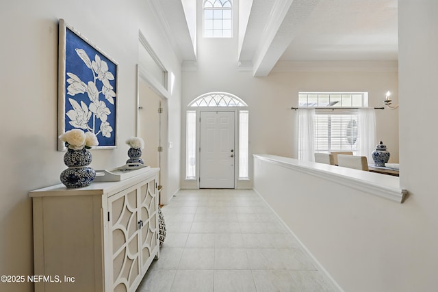 entryway with beamed ceiling, light tile patterned floors, baseboards, and ornamental molding