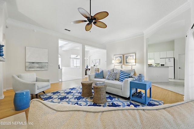 living area featuring ornamental molding, visible vents, light wood finished floors, and ceiling fan