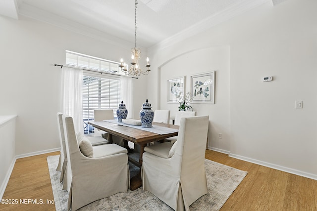 dining space featuring light wood-style flooring, crown molding, and an inviting chandelier