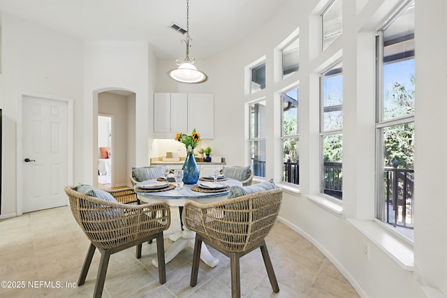 dining area with arched walkways, visible vents, a high ceiling, and light tile patterned floors