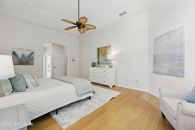 bedroom with a ceiling fan, visible vents, baseboards, arched walkways, and light wood-type flooring