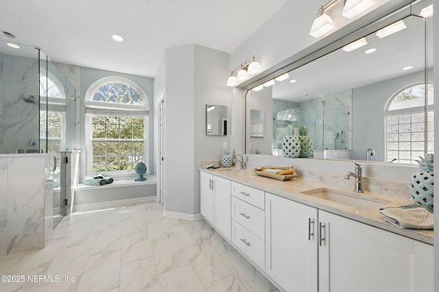 full bath with marble finish floor, a sink, recessed lighting, a marble finish shower, and double vanity