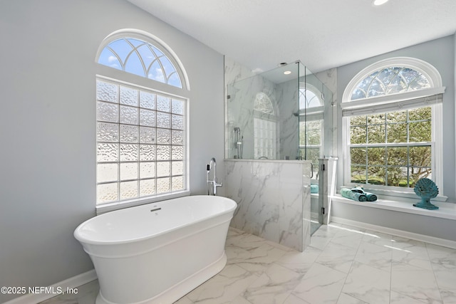 full bathroom featuring a freestanding tub, marble finish floor, and a wealth of natural light