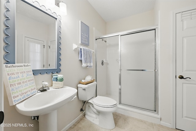 full bathroom featuring tile patterned flooring, a shower stall, a textured ceiling, and toilet