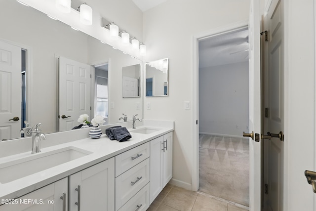 bathroom featuring a sink, baseboards, double vanity, and tile patterned floors