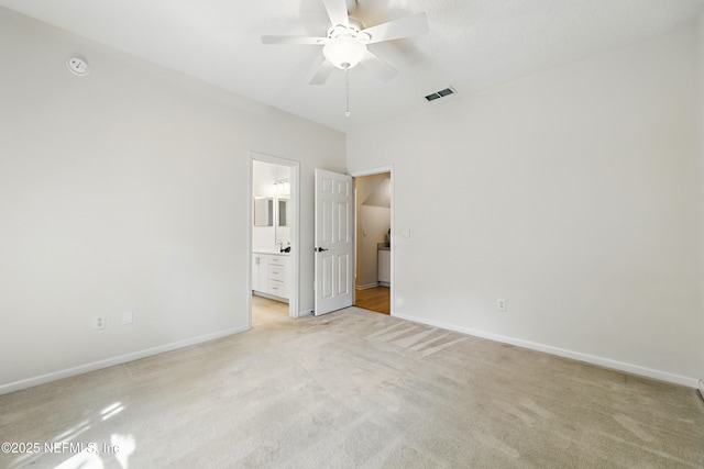 unfurnished bedroom featuring visible vents, connected bathroom, baseboards, light carpet, and a ceiling fan