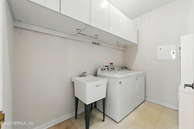 laundry room featuring washer and dryer, cabinet space, baseboards, and a textured ceiling