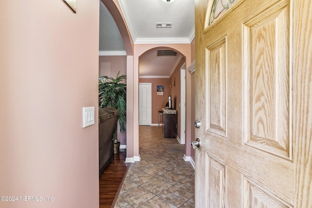 hallway with visible vents, arched walkways, baseboards, and ornamental molding