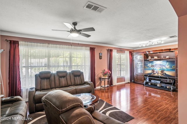 living room featuring ornamental molding, visible vents, a textured ceiling, and wood finished floors