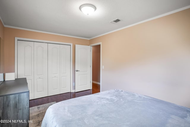 bedroom featuring dark wood-type flooring, a closet, visible vents, and crown molding