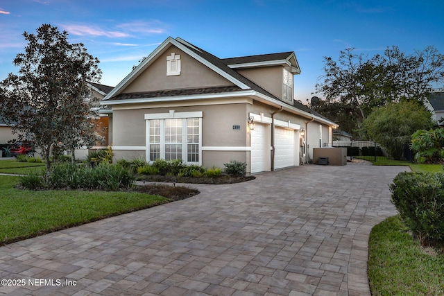 view of front facade with decorative driveway, fence, and stucco siding