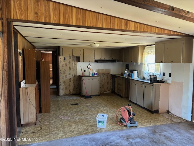 kitchen with a sink, light floors, and beam ceiling