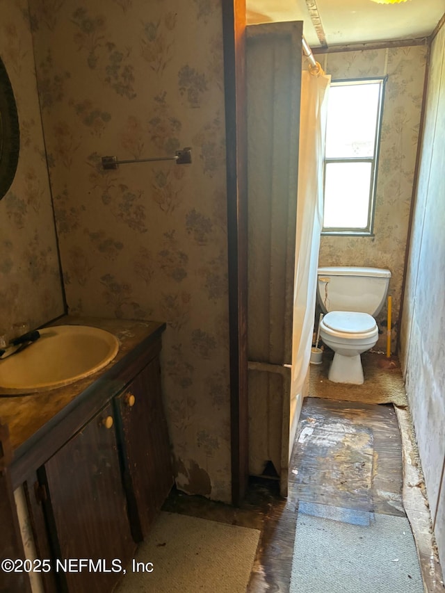 bathroom with vanity, toilet, and wallpapered walls