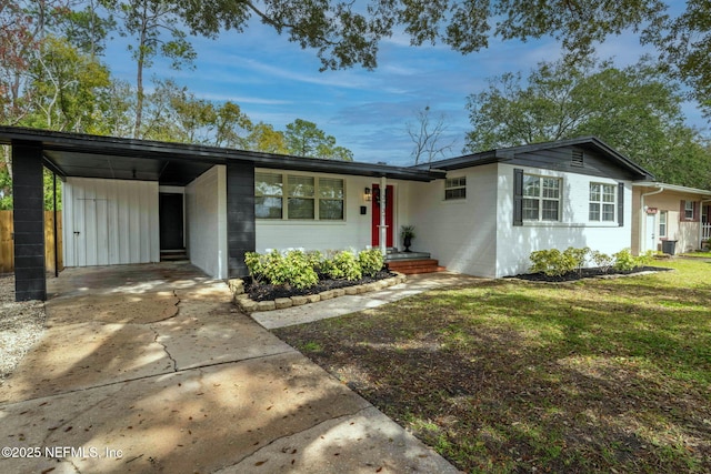 view of front of property featuring driveway, concrete block siding, a carport, and a front yard