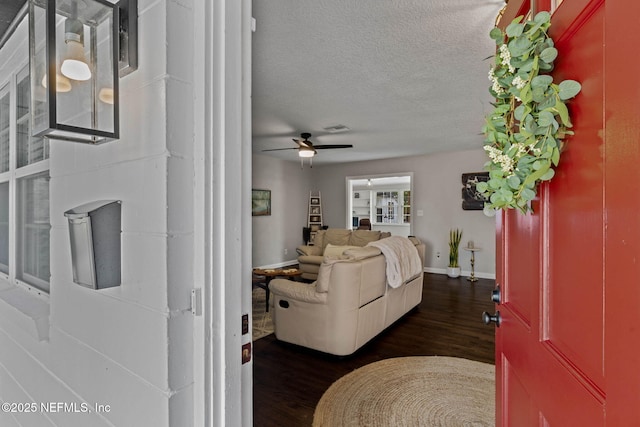 living room featuring visible vents, baseboards, a ceiling fan, dark wood-style floors, and a textured ceiling