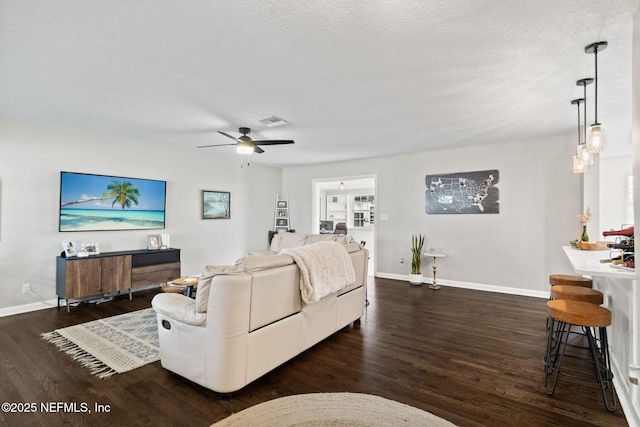 living room with visible vents, dark wood finished floors, a textured ceiling, and baseboards