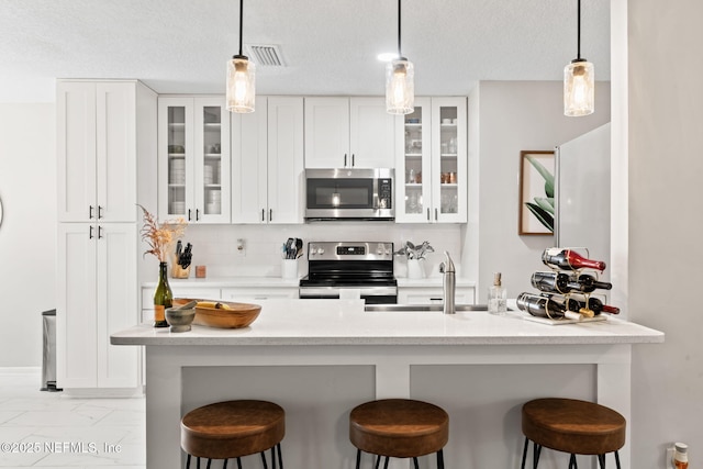 kitchen with visible vents, appliances with stainless steel finishes, marble finish floor, a kitchen bar, and a sink