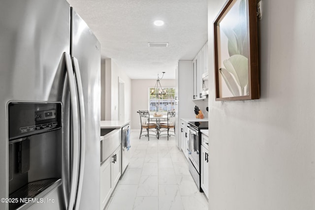 kitchen with white cabinets, marble finish floor, stainless steel appliances, and light countertops