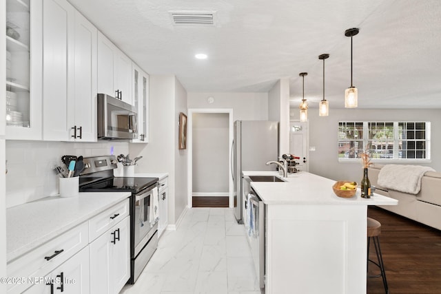 kitchen with a breakfast bar, visible vents, light countertops, appliances with stainless steel finishes, and decorative backsplash