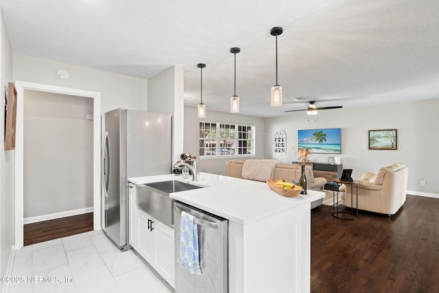 kitchen with light countertops, a ceiling fan, freestanding refrigerator, open floor plan, and white cabinets