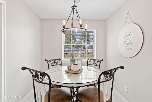 dining room featuring a chandelier and baseboards