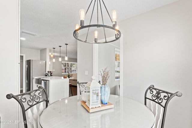 dining space featuring a textured ceiling, visible vents, and a notable chandelier