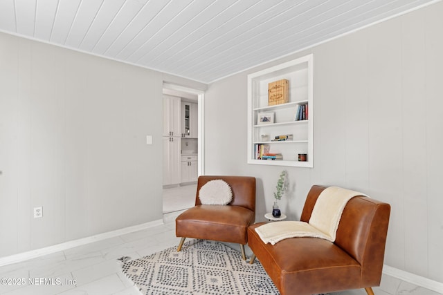 living area with built in shelves, marble finish floor, and baseboards