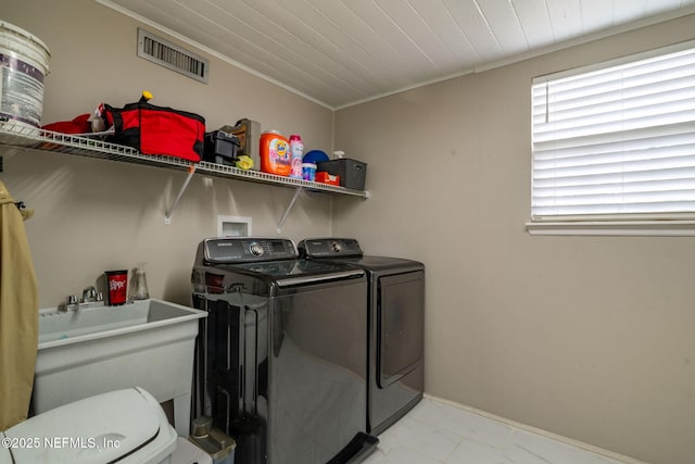 laundry area with laundry area, visible vents, crown molding, separate washer and dryer, and a sink