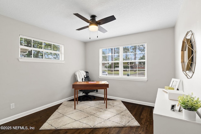 office featuring a textured ceiling, dark wood-type flooring, a ceiling fan, and baseboards