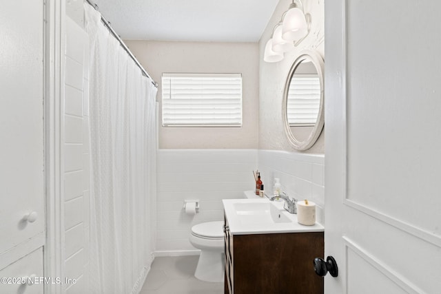 full bathroom with wainscoting, toilet, tile walls, and vanity